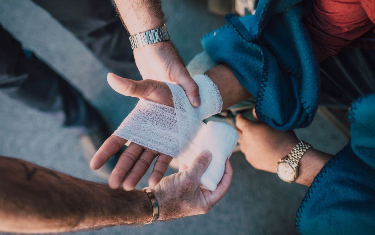 A person has their hand bandaged by another person after a bicycle crash.