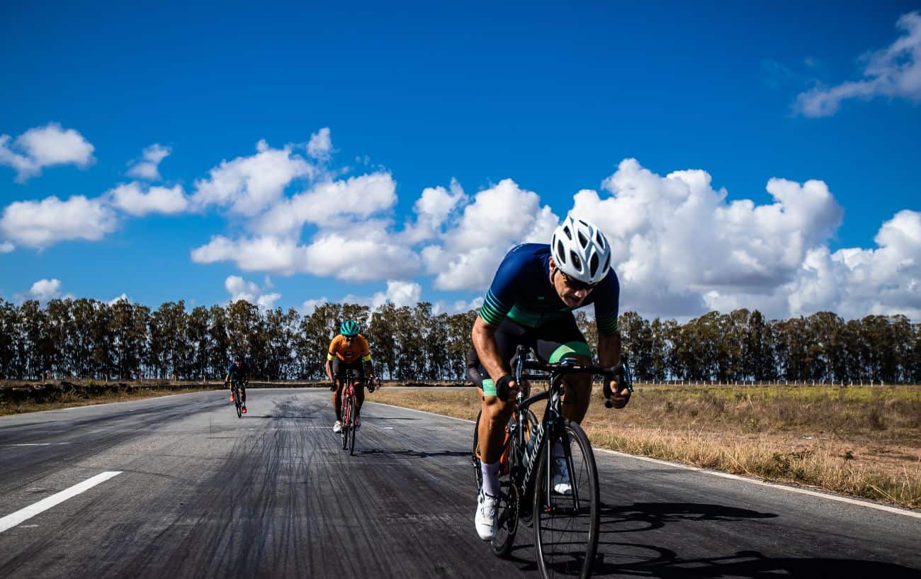 A cyclist on a black road bike sprints during a polarized cardio session on a race track.