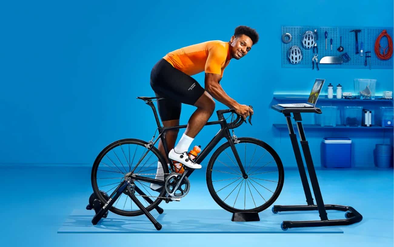 A cyclist in an orange jersey rides a Zwift bike.