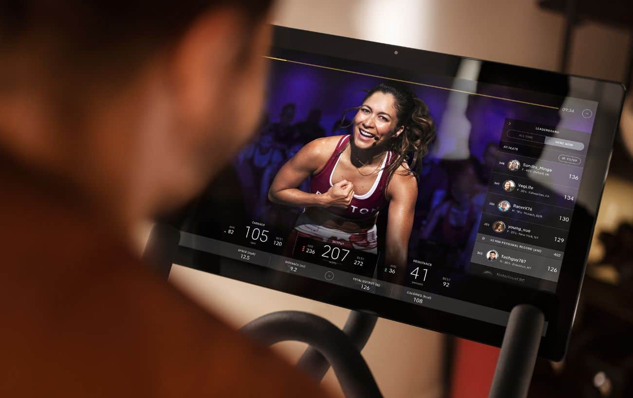 View over a cyclist's shoulder of the screen of a Peloton bike.