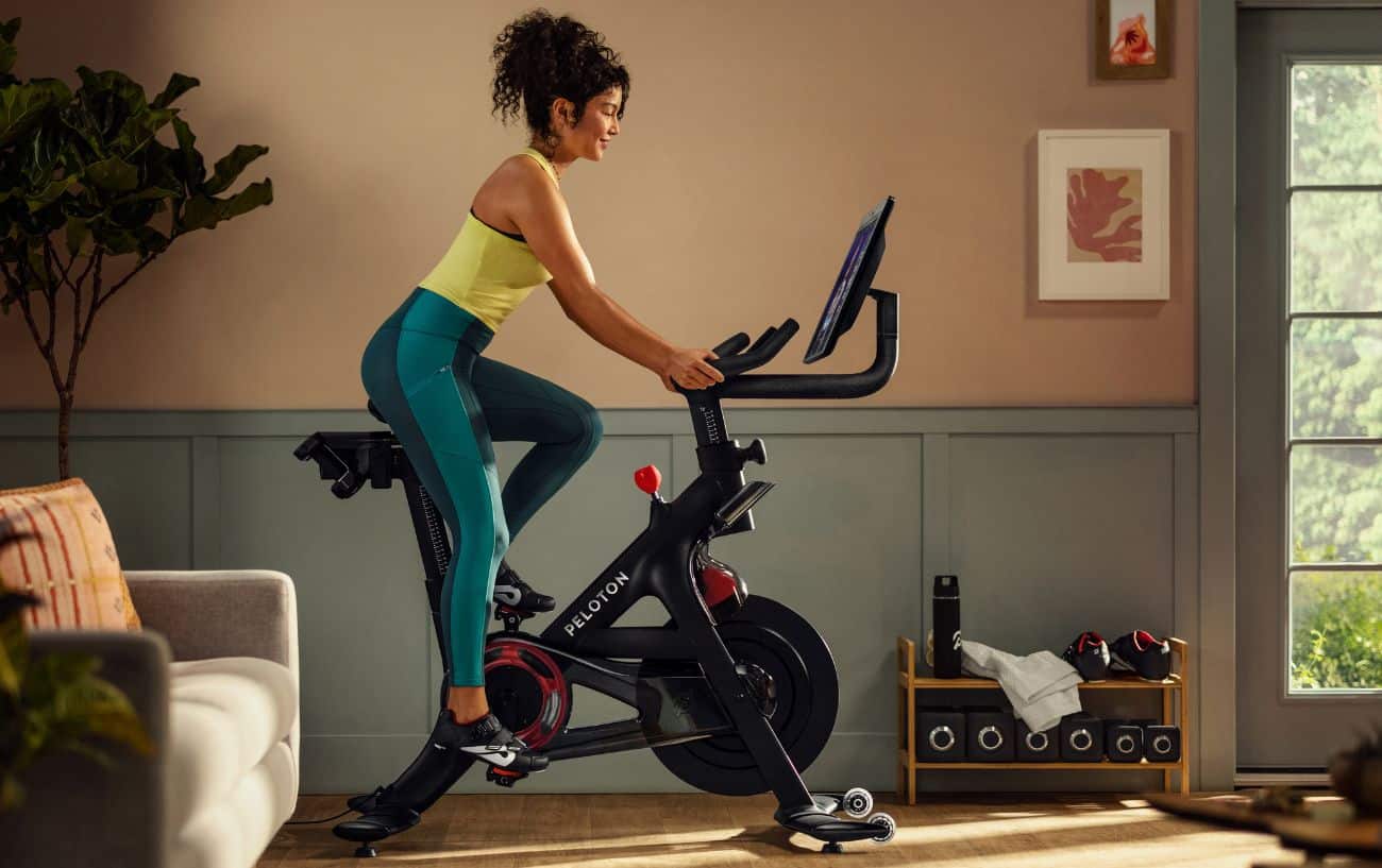 A woman rides her Peloton bike in her living room.