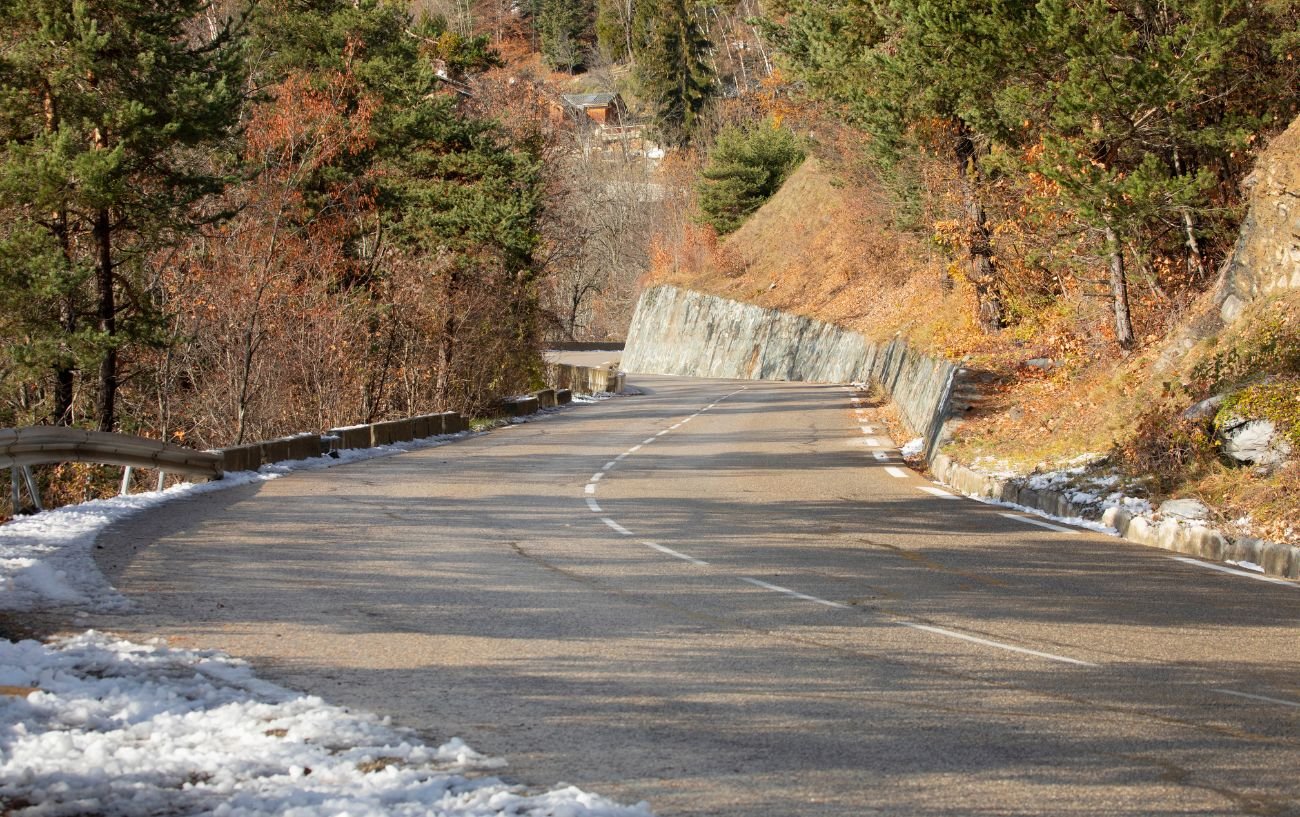 One of the lower sections of the road up to Alpe d'Huez in winter with snow on the embankments.