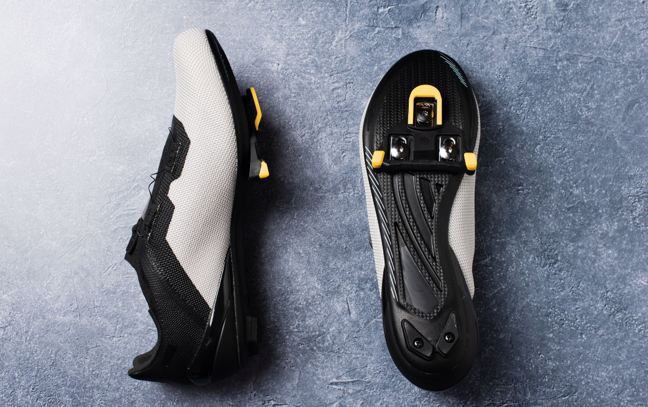 A pair of white Peloton shoes on a granite tabletop with the cleats installed.