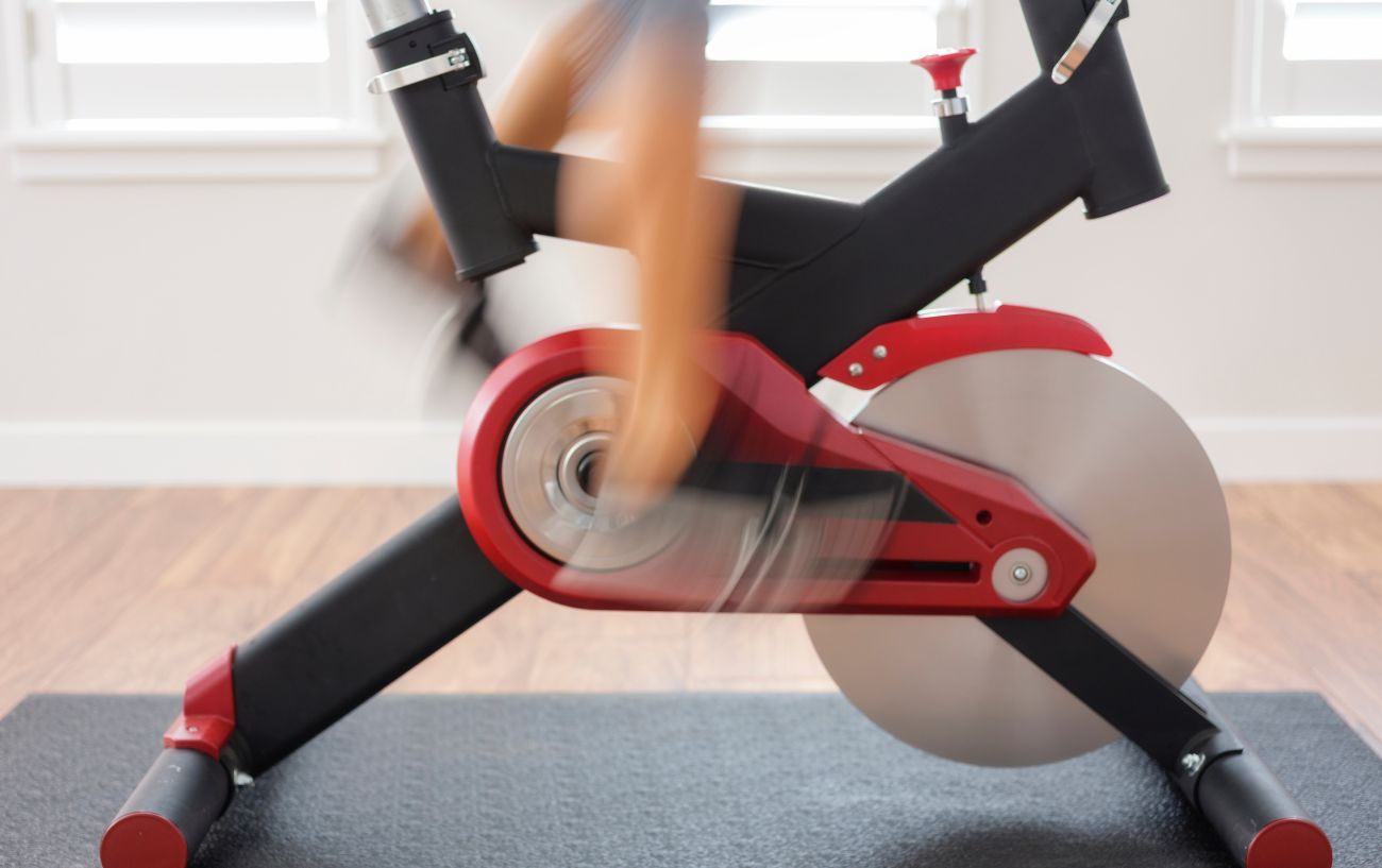 Close-up of a spin bike with blurred legs pedaling.