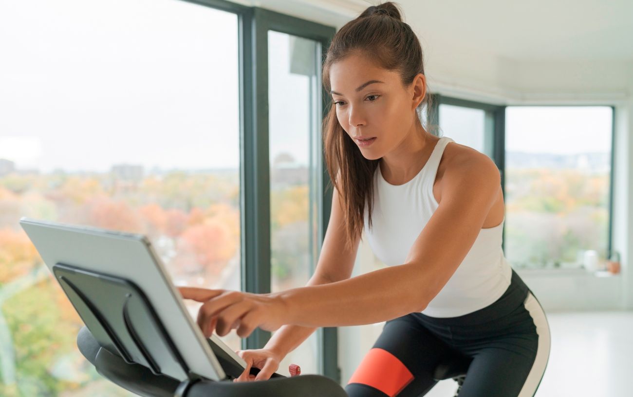 A woman presses the screen of her stationary bike's console.