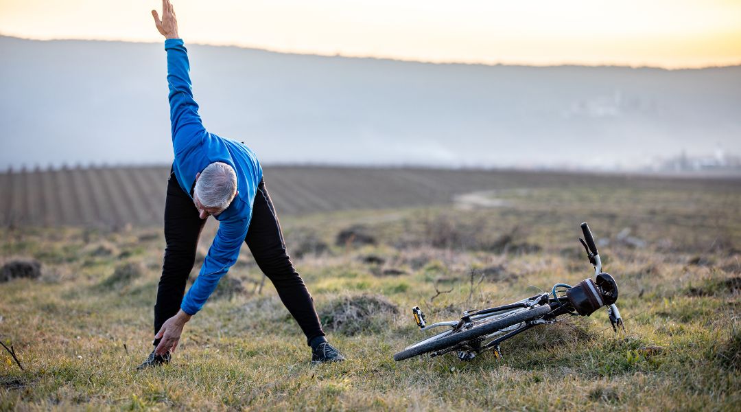 A person doing a dynamic warm-up with their bike on the ground next to them.
