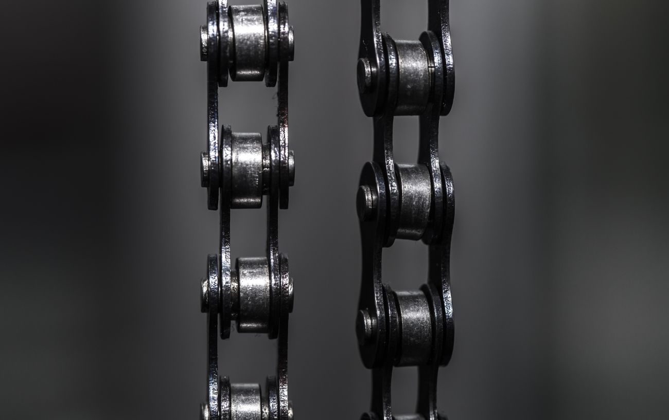 Close-up photo of a bike chain against a soft-focus grey background.