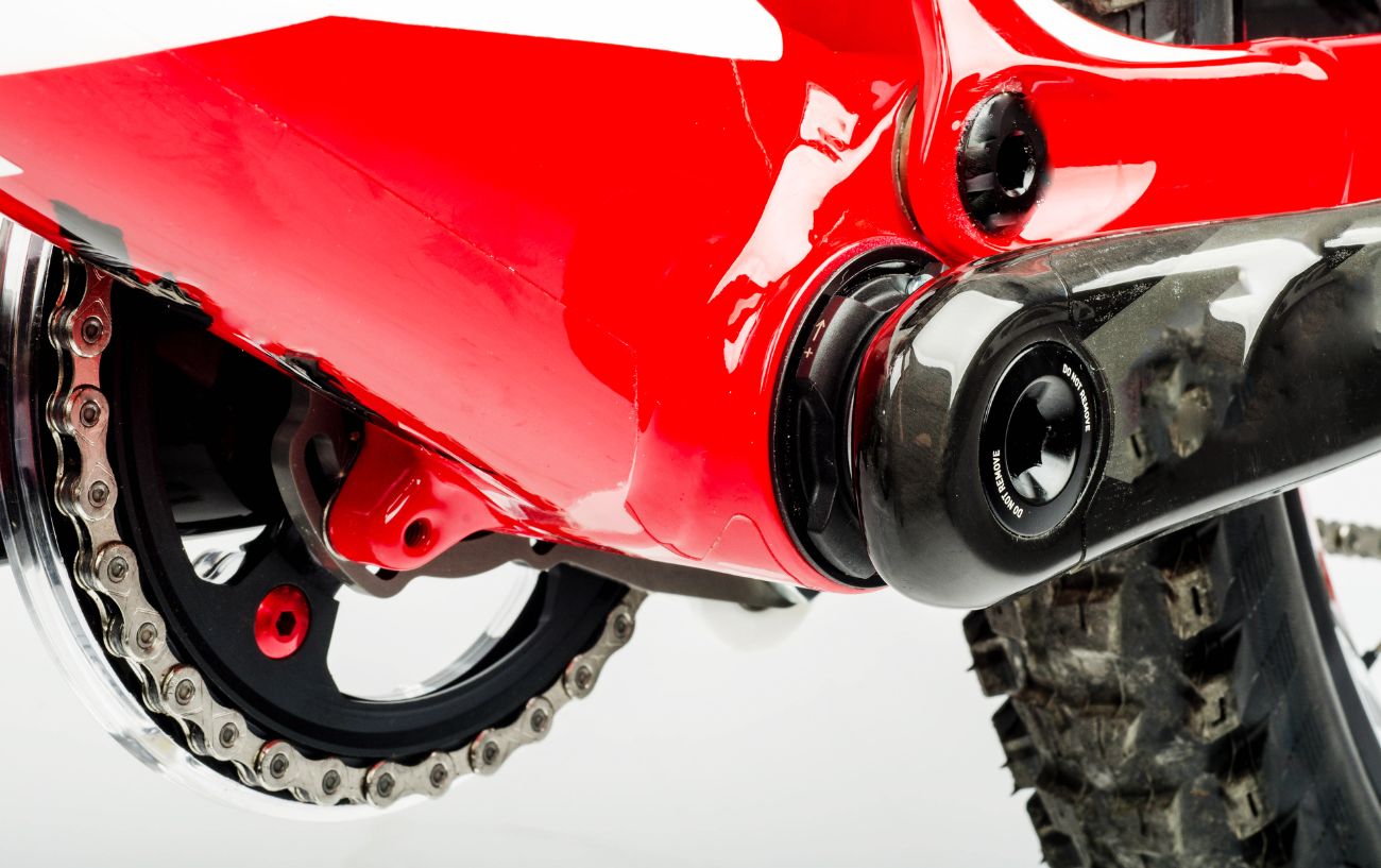 Close-up of a narrow wide chainring on a red mountain bike.