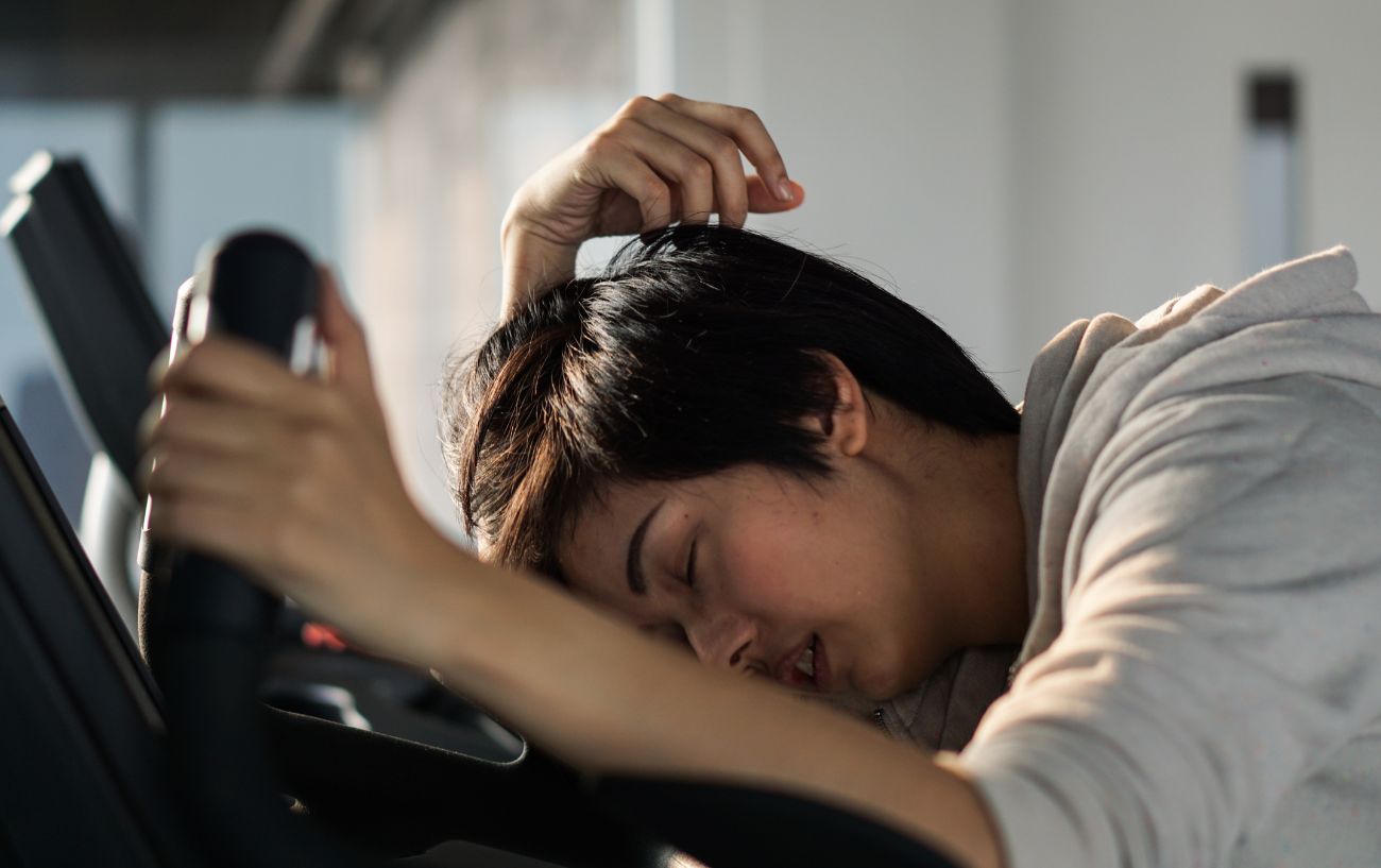 What Is Bonking In Cycling - And How Do You Avoid It? 3 A cyclist in a white jersey is passed out on an exercise bike.