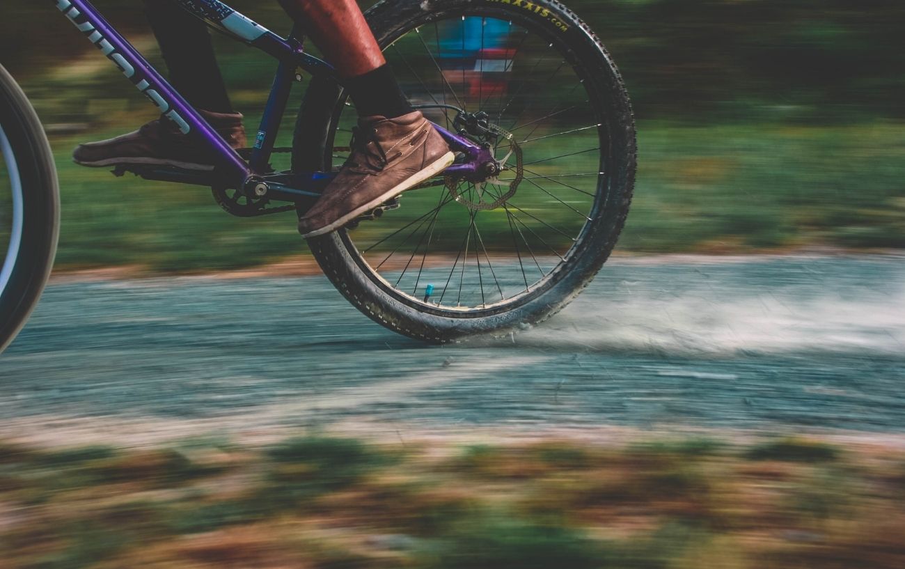 A purple gravel bike with a 1x drivetrain skids on a dirt path.