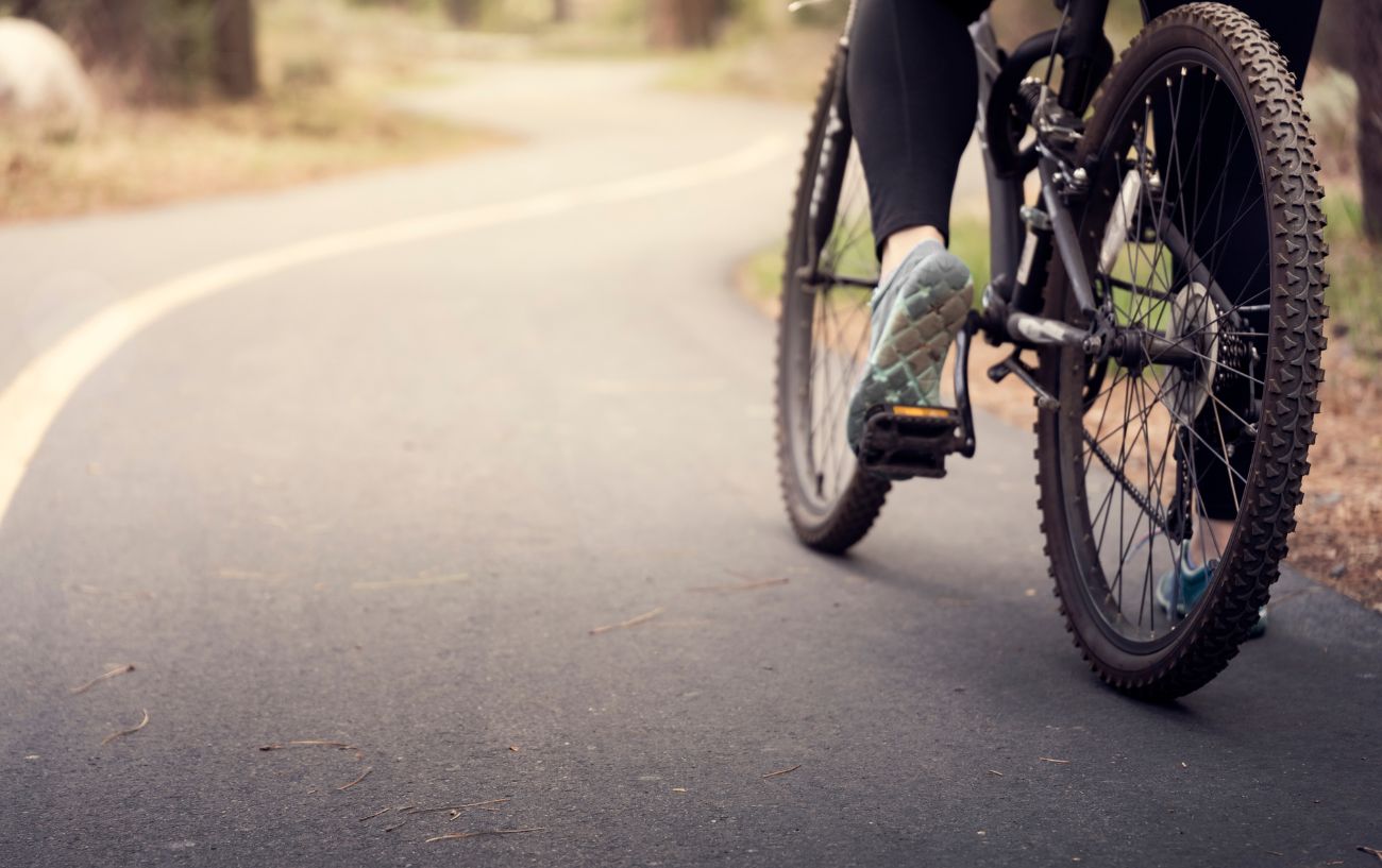 A black gravel bike with 29-inch wheels being ridden on an asphalt path.