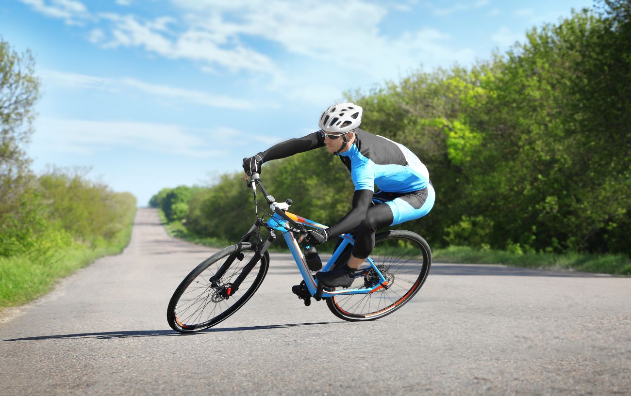 A cyclist rides a blue gravel bike with 700c wheels on a paved road.