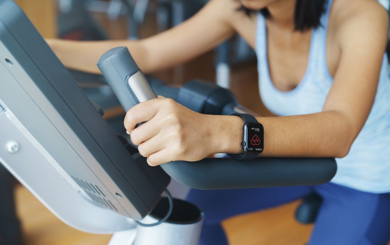 A woman rides an exercise bike after fixing her Apple Watch not connecting to Peloton issue.
