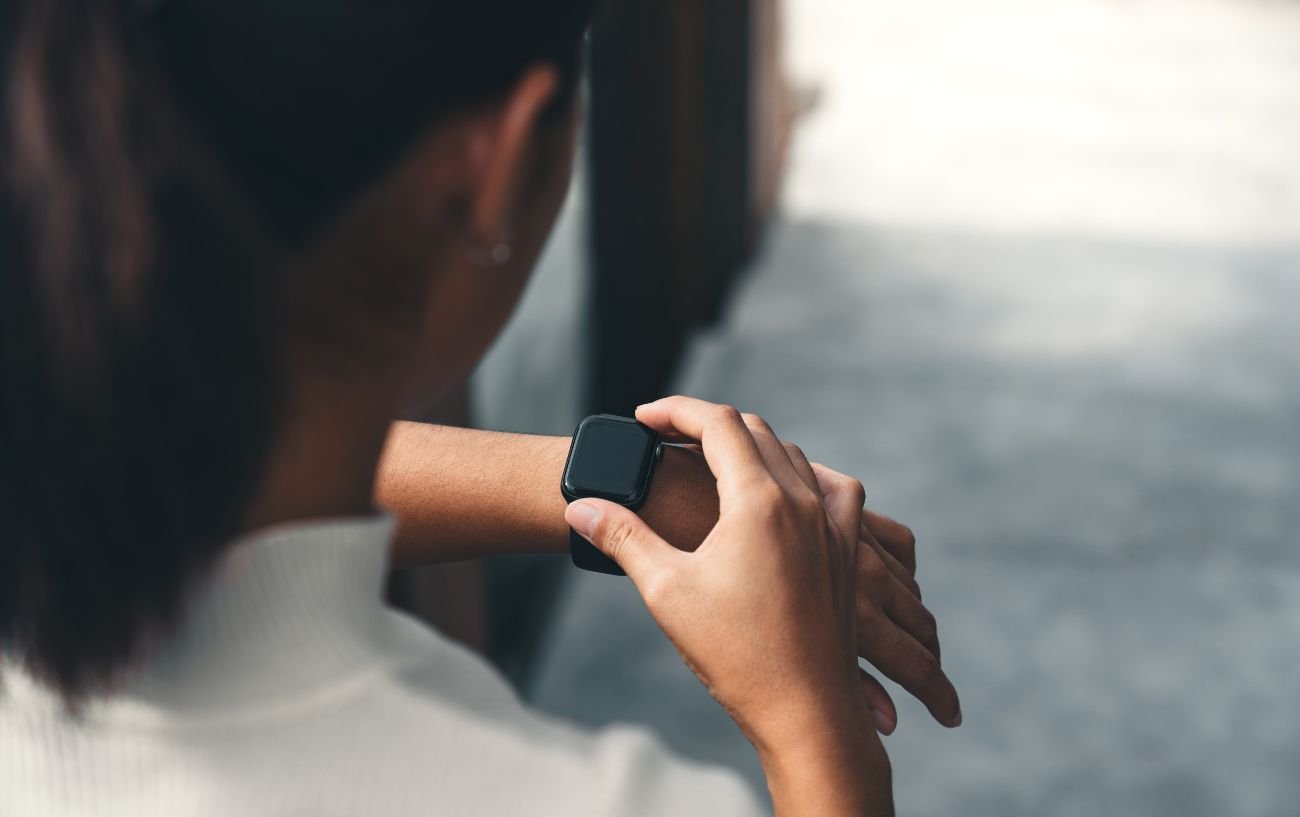 A woman in a white top restarts her Apple Watch.