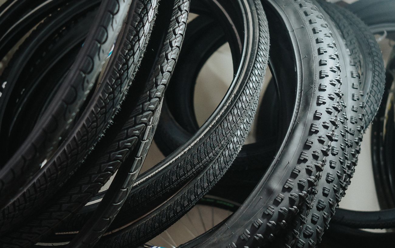 Different types of bike tires piled up on the floor of a garage.