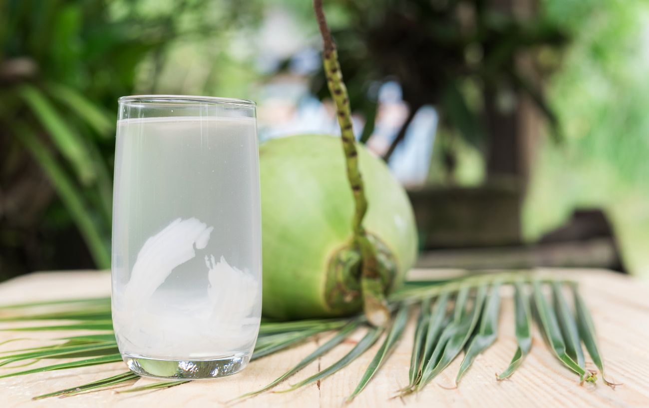 A glass of coconut water with coconut shavings floating within.