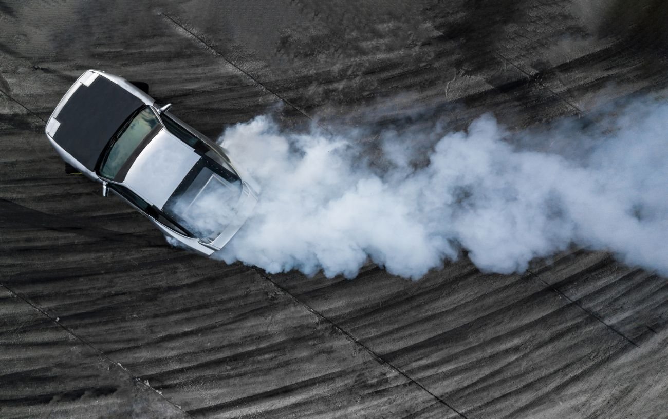 A silver sports car drifts at a race track.