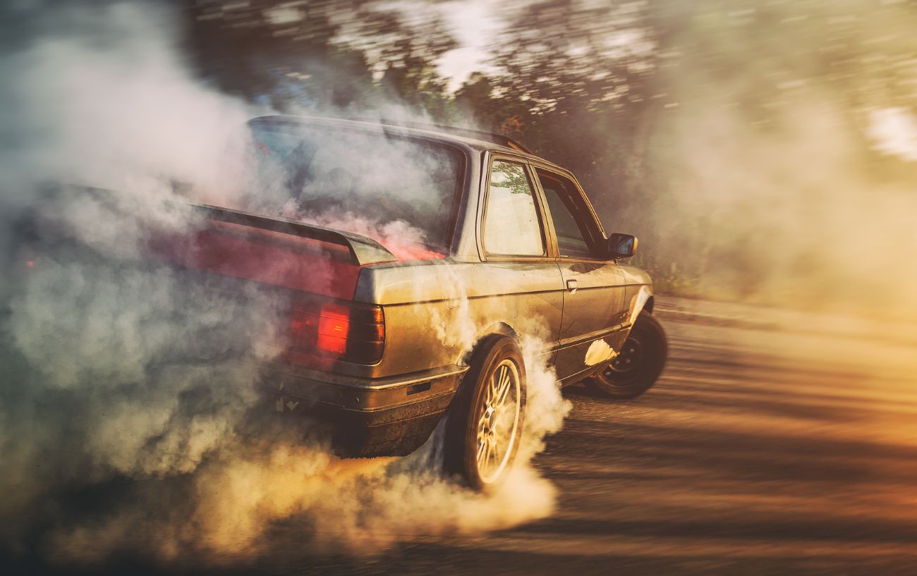 A car drifting on an asphalt road at sunset.