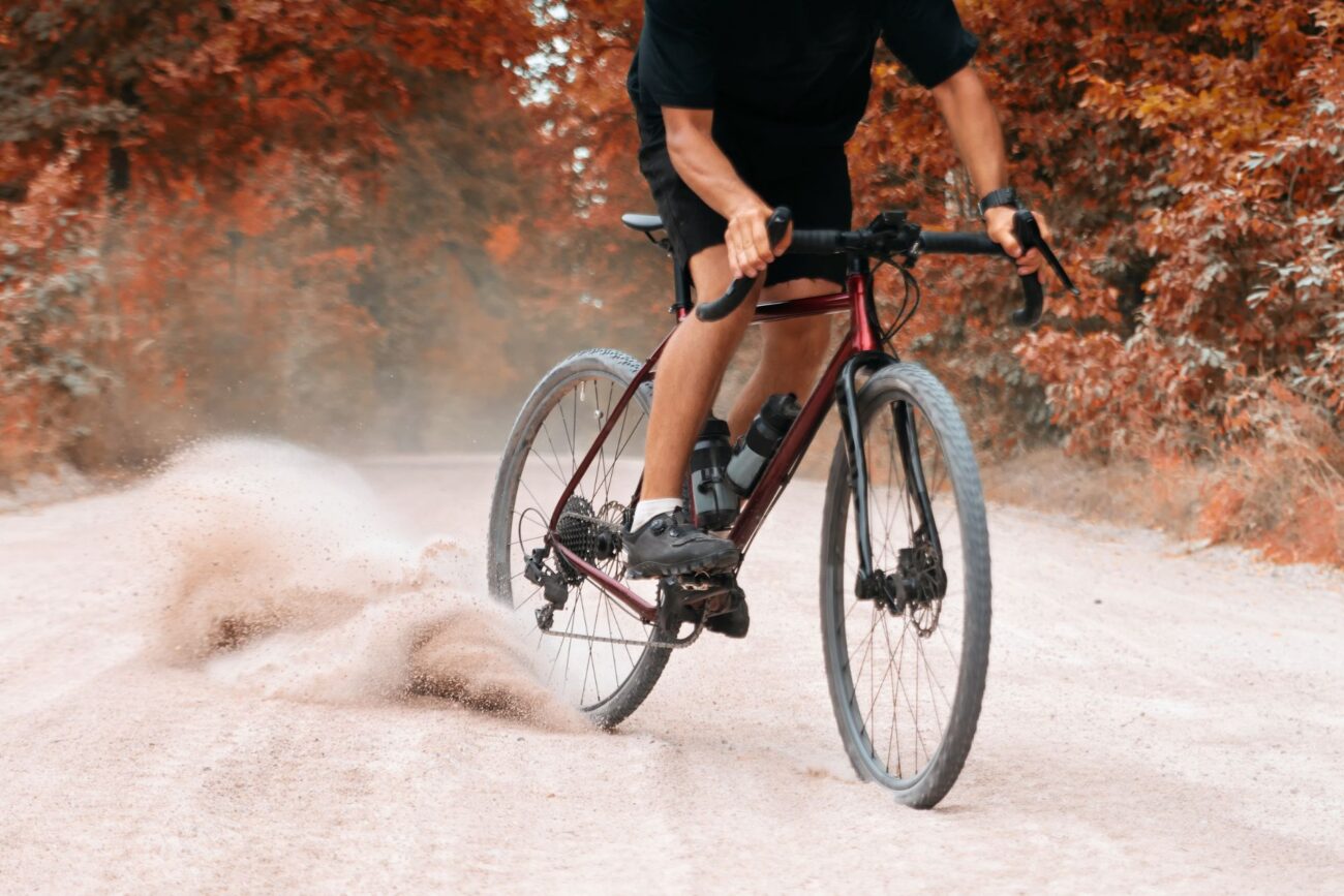 A burgundy gravel bike drifting on a loose dirt trail.