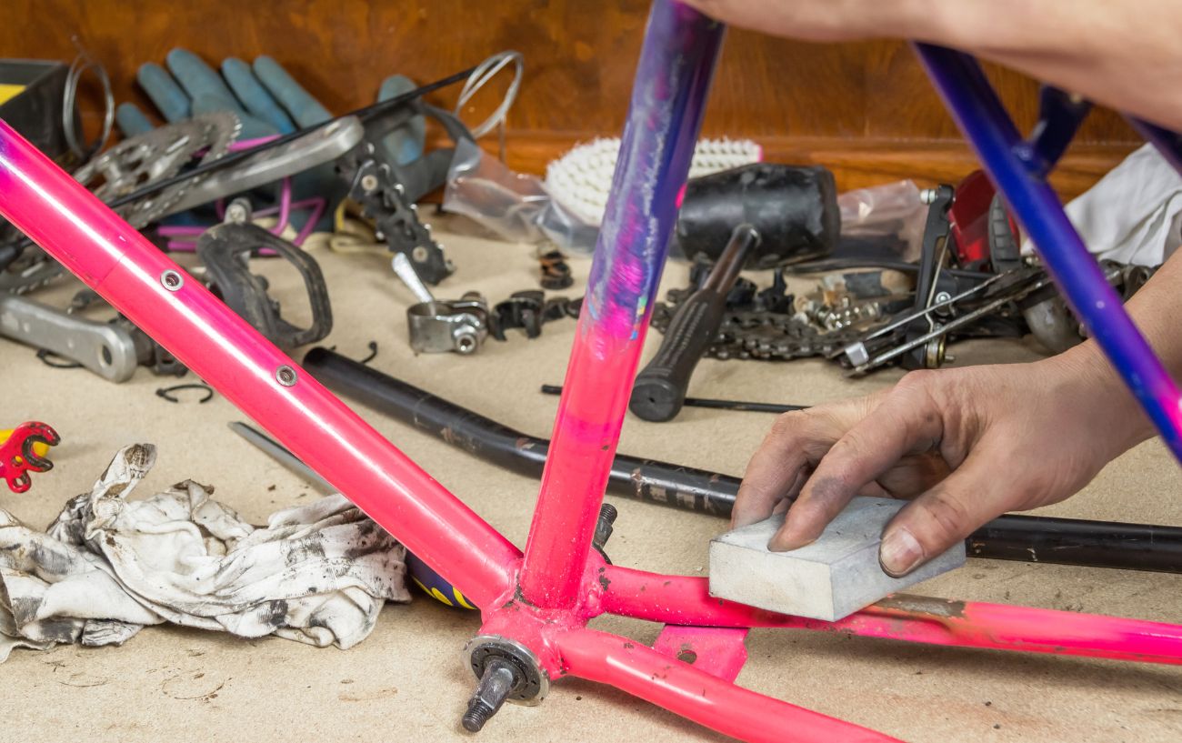 A mechanic restores a pink road bike frame.