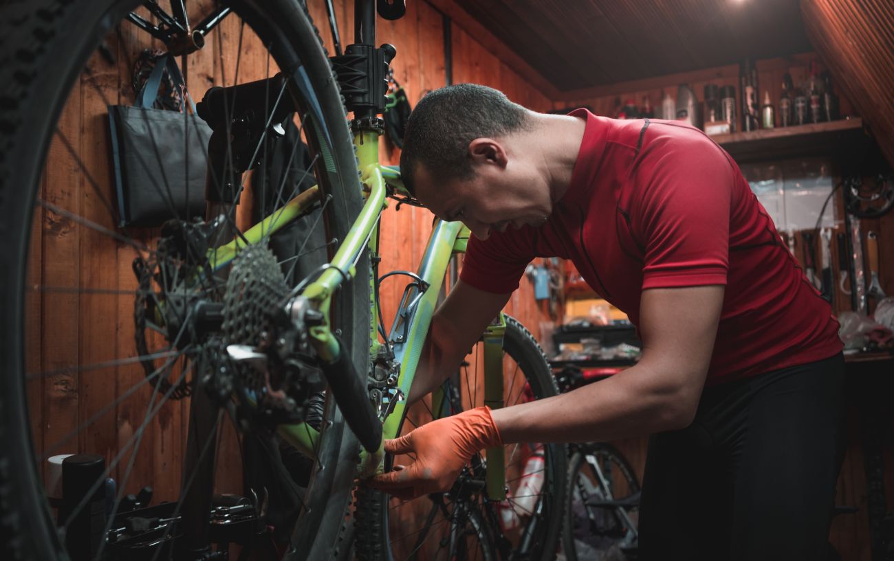 A cyclist works on restoring his green mountain bike in his garage.