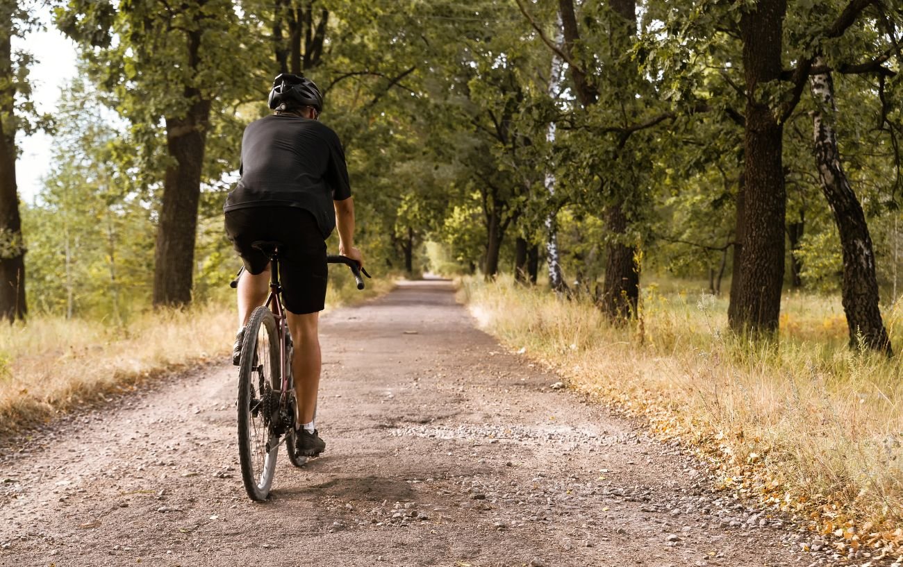 A cyclist on a gravel bike rides through a forest.
