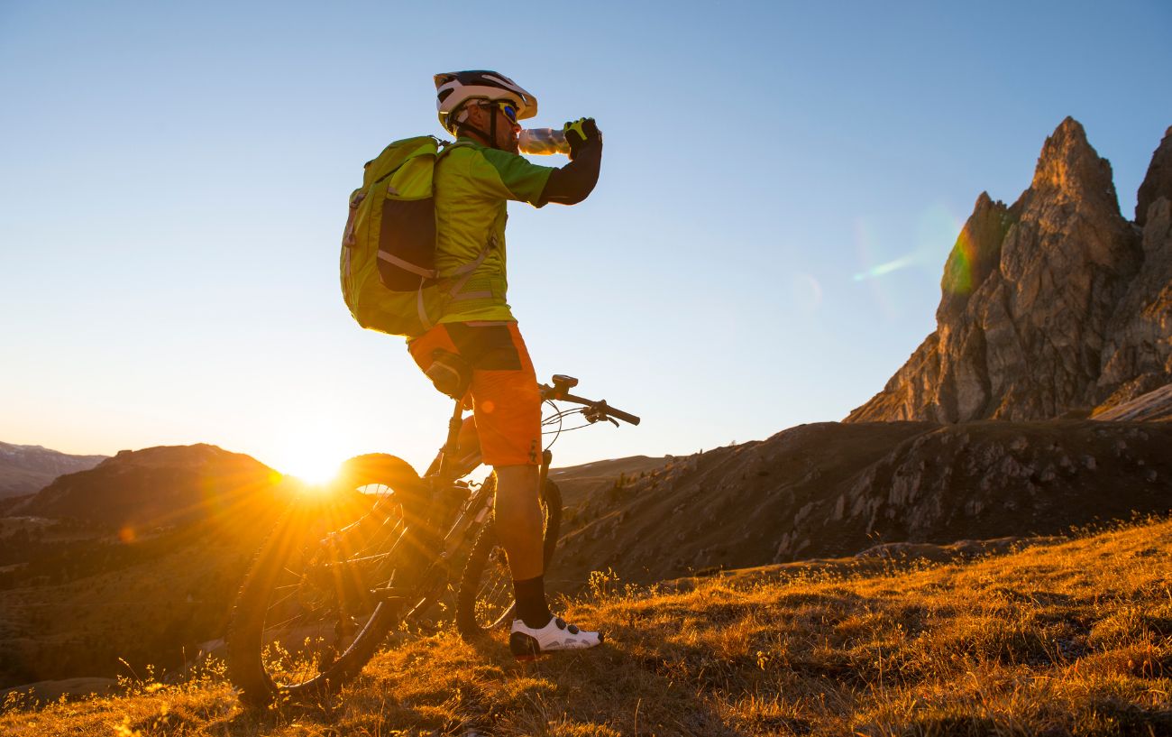 A cyclist on a mountain bike pauses to sip from a homemade energy drink.