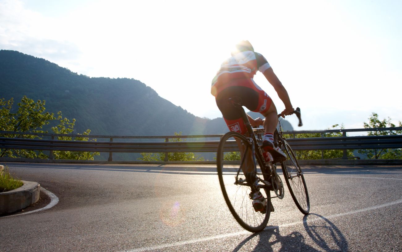 A cyclist on a road bike rides up a steep hill.