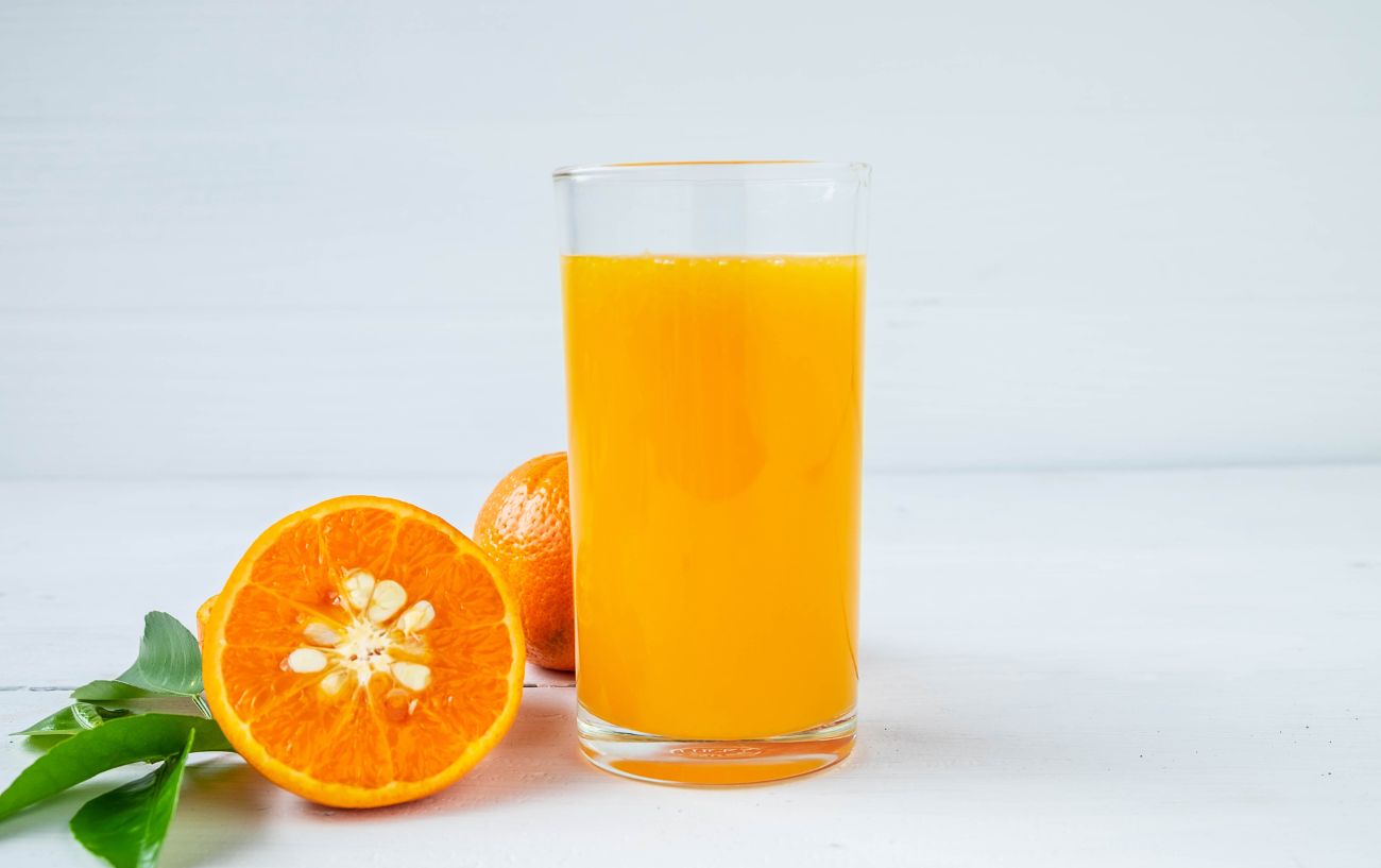 A glass of orange juice sits next to a halved orange.