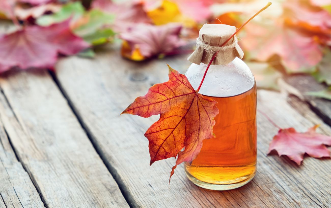 A jar of maple syrup sits on a wooden bench.