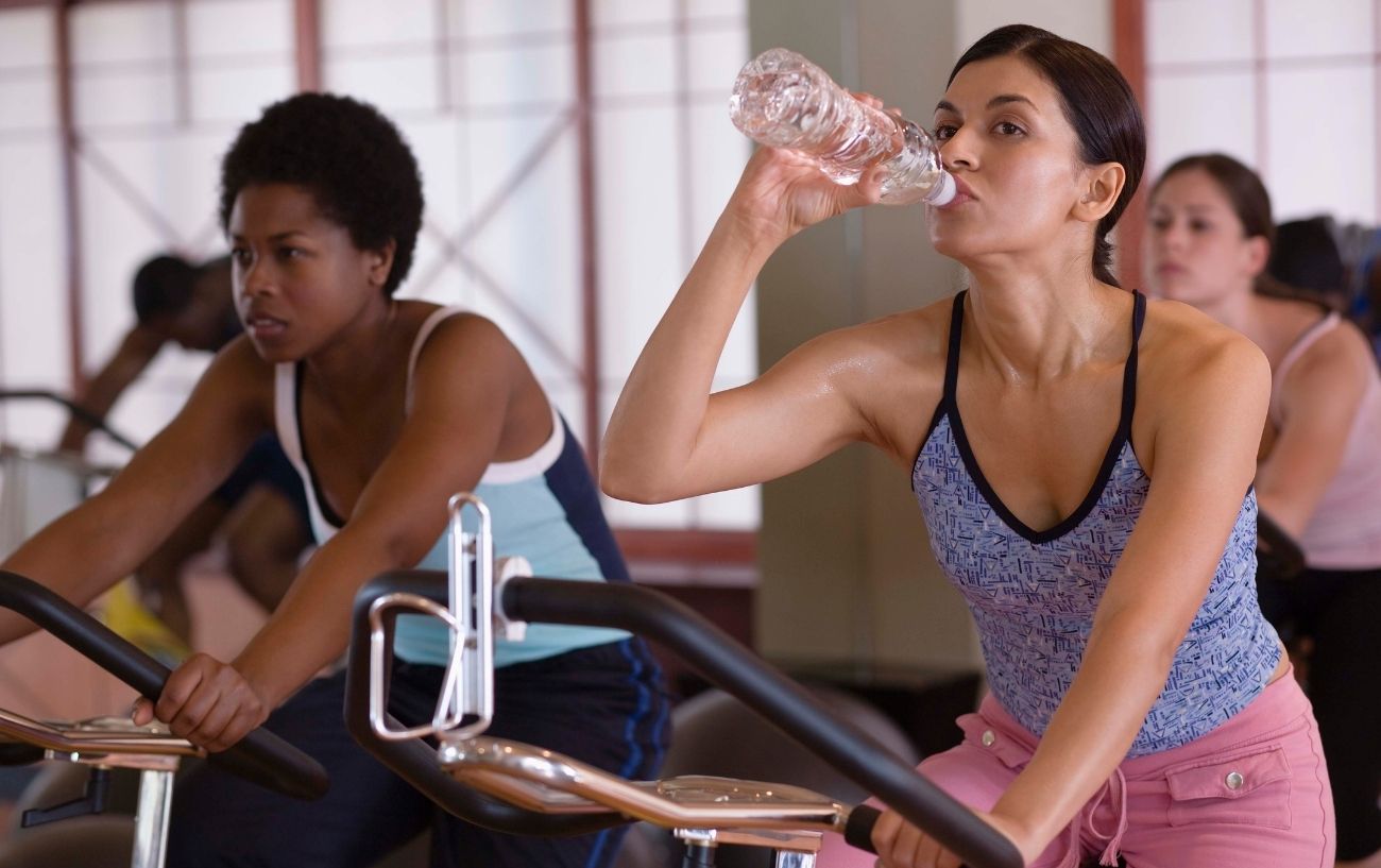 Two women take a break during a spin class.