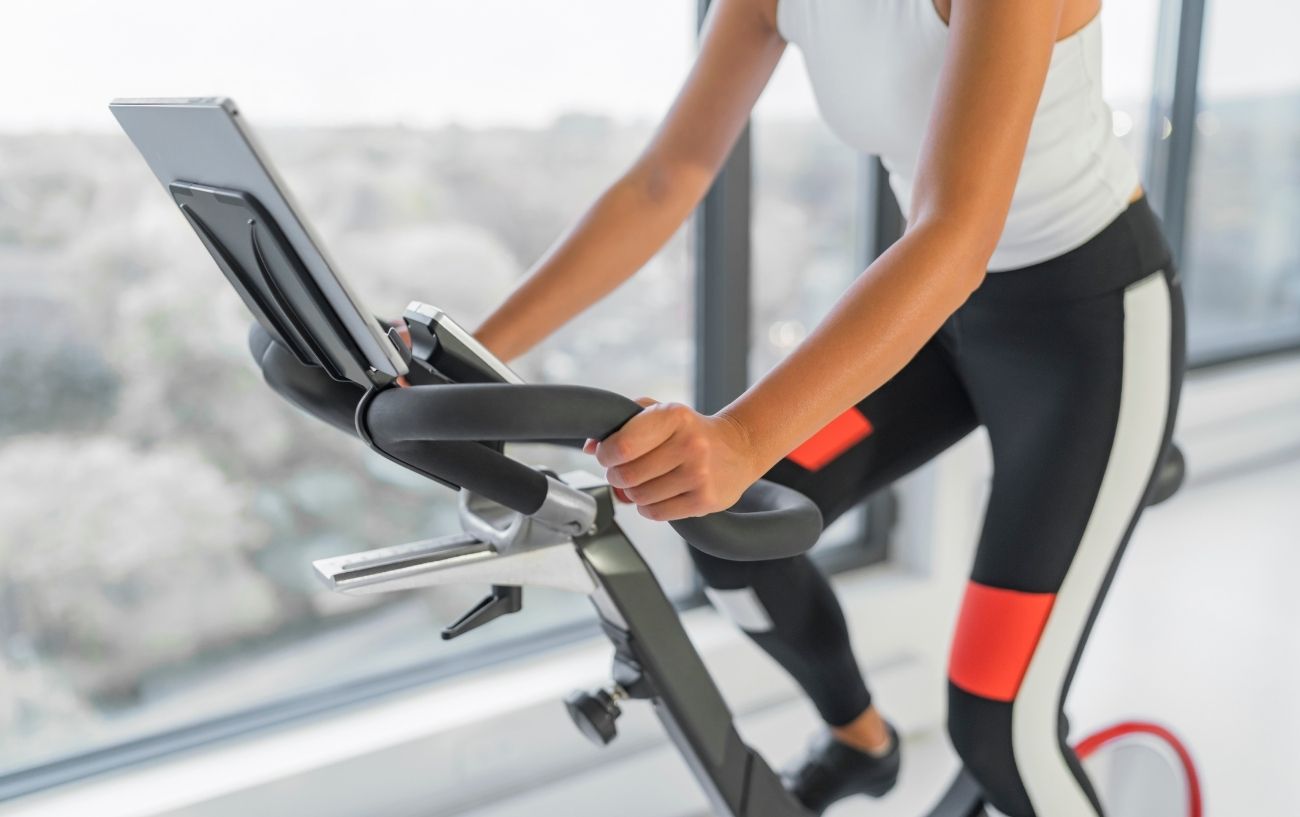 Close-up of a cyclist in black leggings on a spin bike.