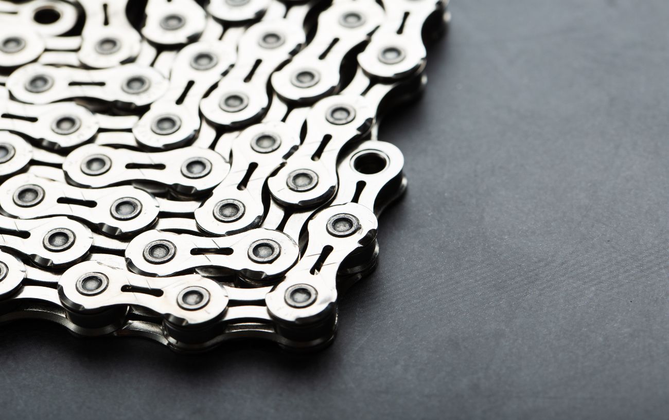 Close-up of a silver bike chain on a grey background.