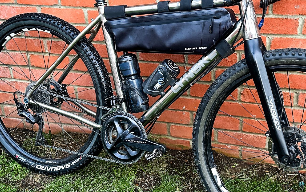 A gravel bike rests against a brick wall.