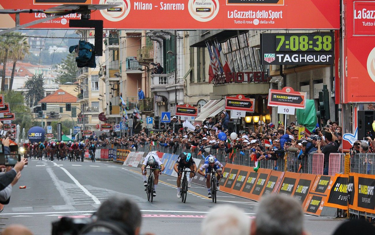 Three cyclists cross the finish line at Milan-San Remo.