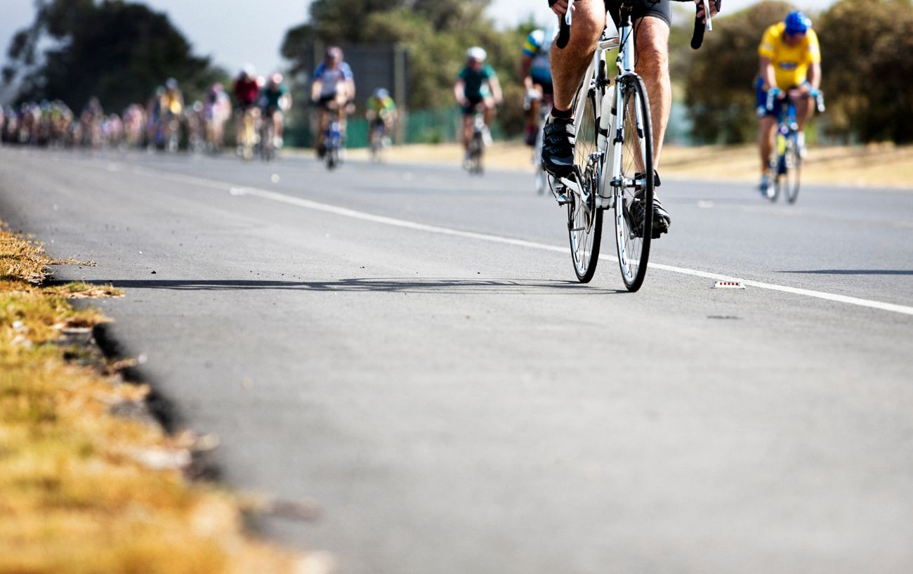 A cyclist on a white road bike leads the pack at a Gran Fondo.