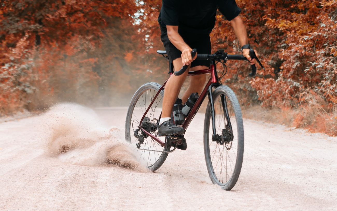 A cyclist skids on a burgundy gravel bike during fall.