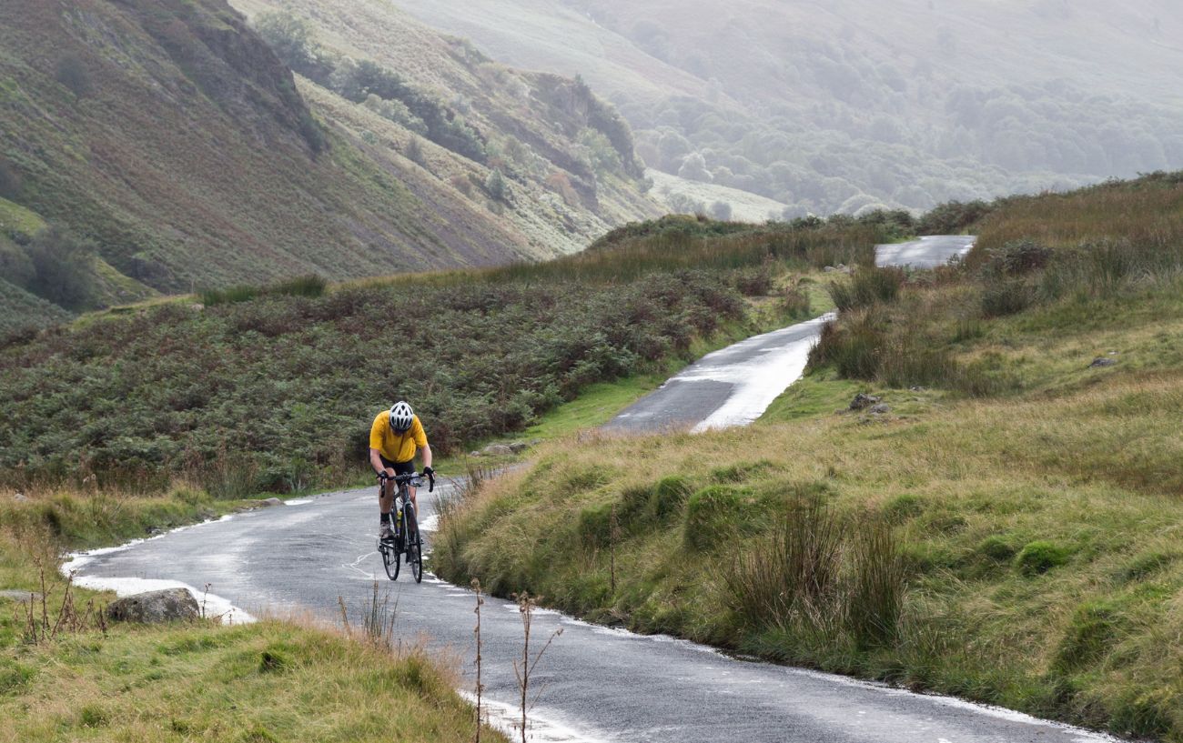A cyclist in an orange jersey tackles the Hardknott Pass cycle.