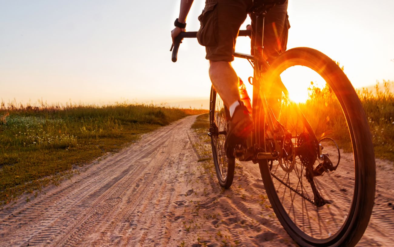 A gravel bike riding on a sandy path at sunset.