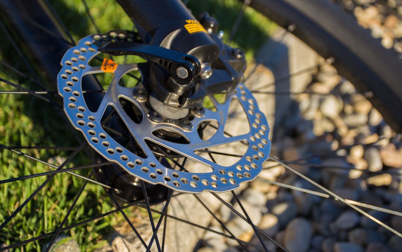 A mountain bike with hydraulic disc brakes rests on a gravel path.