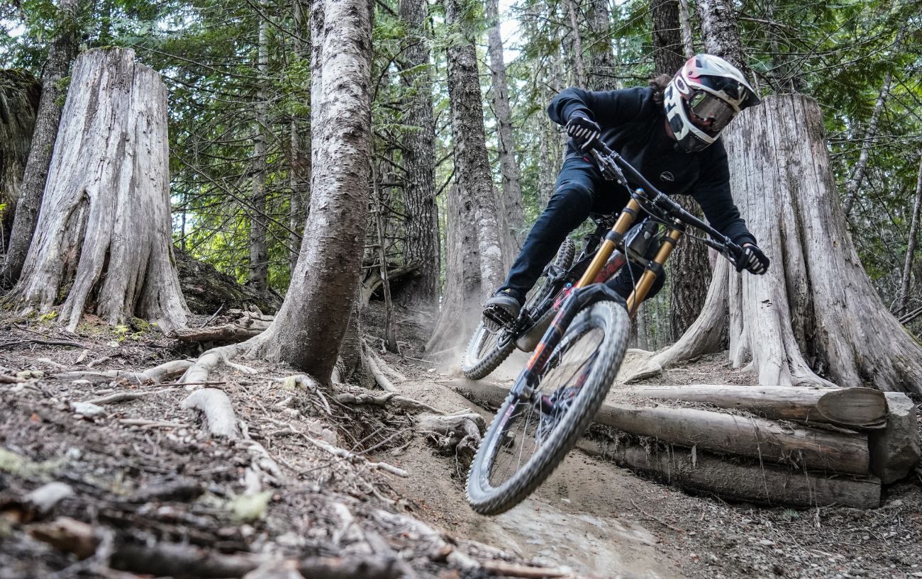 A cyclist flies through a forest on a mountain bike.