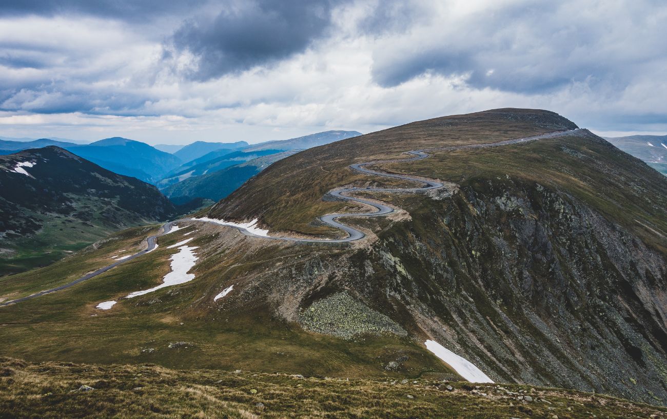 A road snakes across a mountain in Transalpina, Romania.