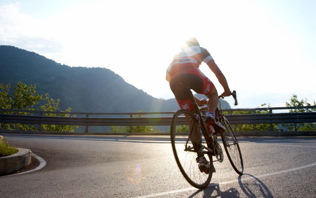 A road cyclist rounds a hairpin bend on a mountain road.
