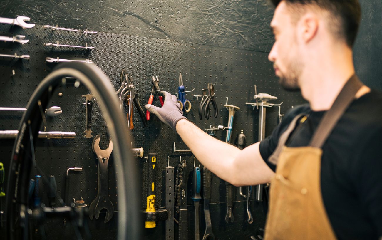 A bike mechanic reaches for some pliers from his bike tool rack.
