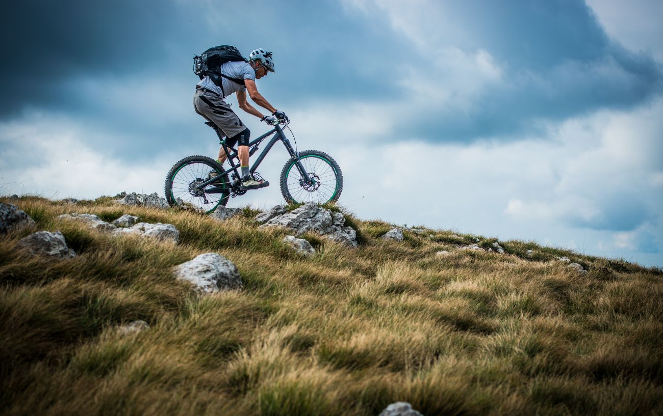 A cyclist rides down a rocky hill on a mountain bike.