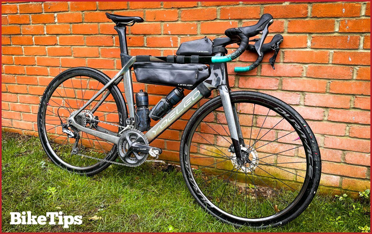 A grey bike with a freshly-cleaned chain leans against a brick wall.