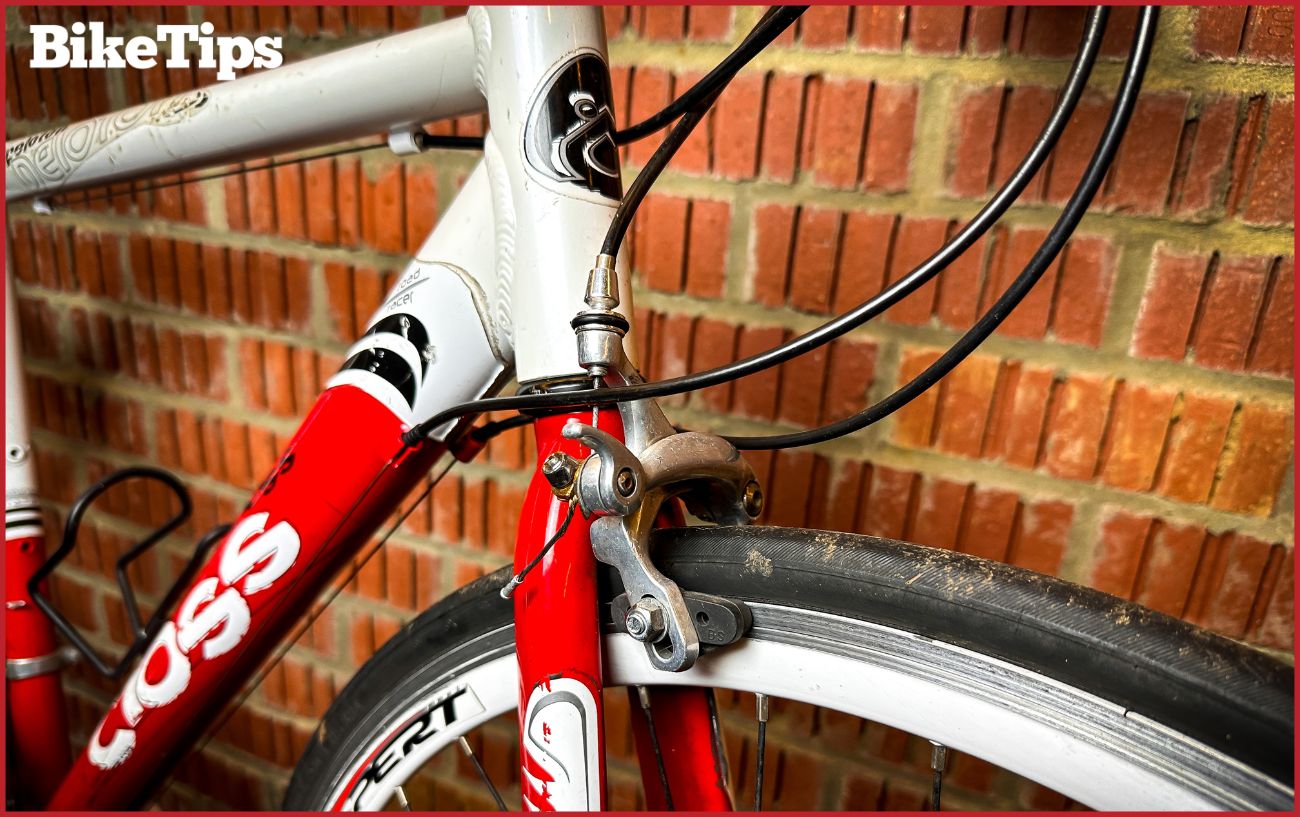 The front end of a road bike with brake cables showing.