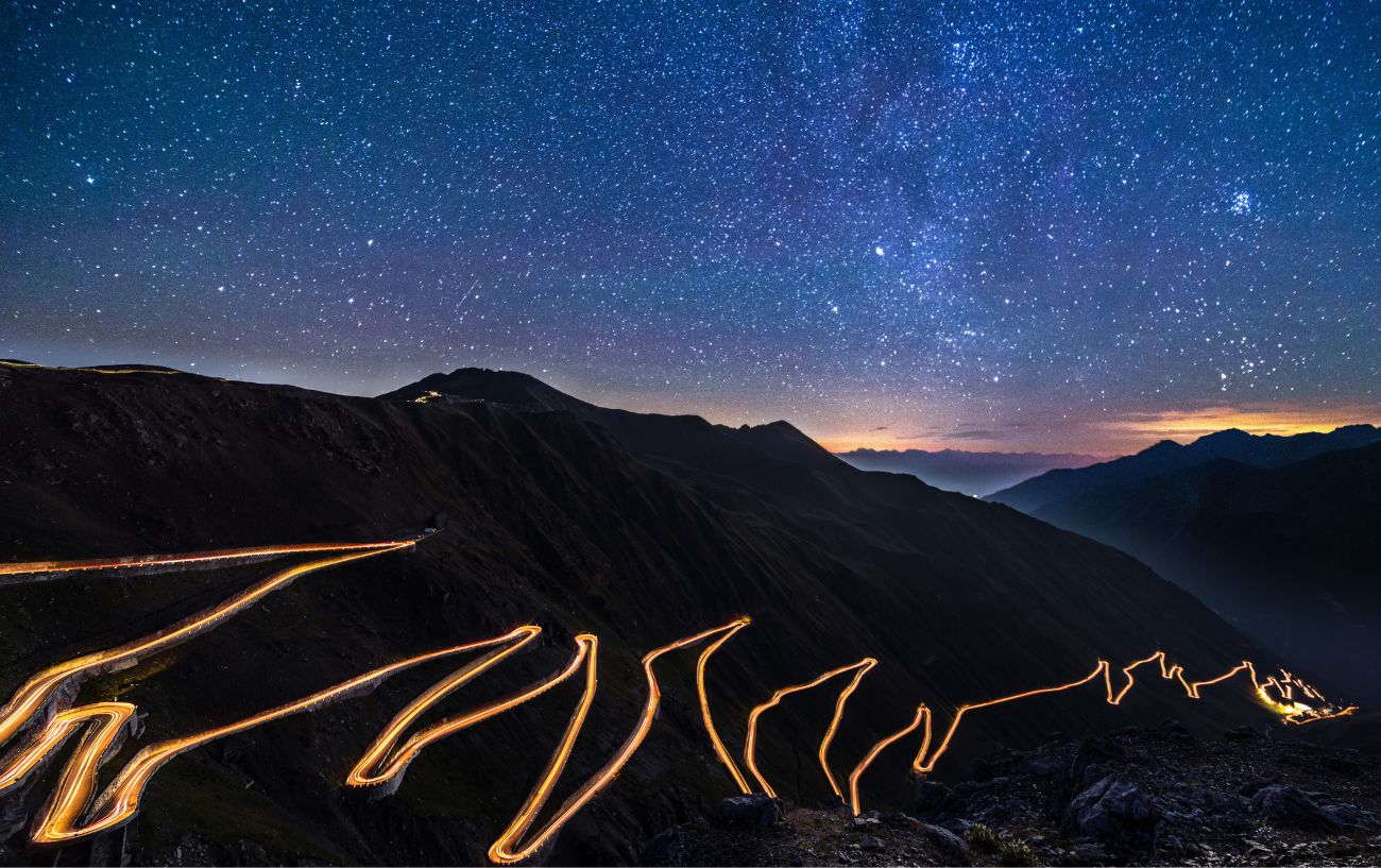 A night view of the Stelvio Pass with the road lit by headlights.