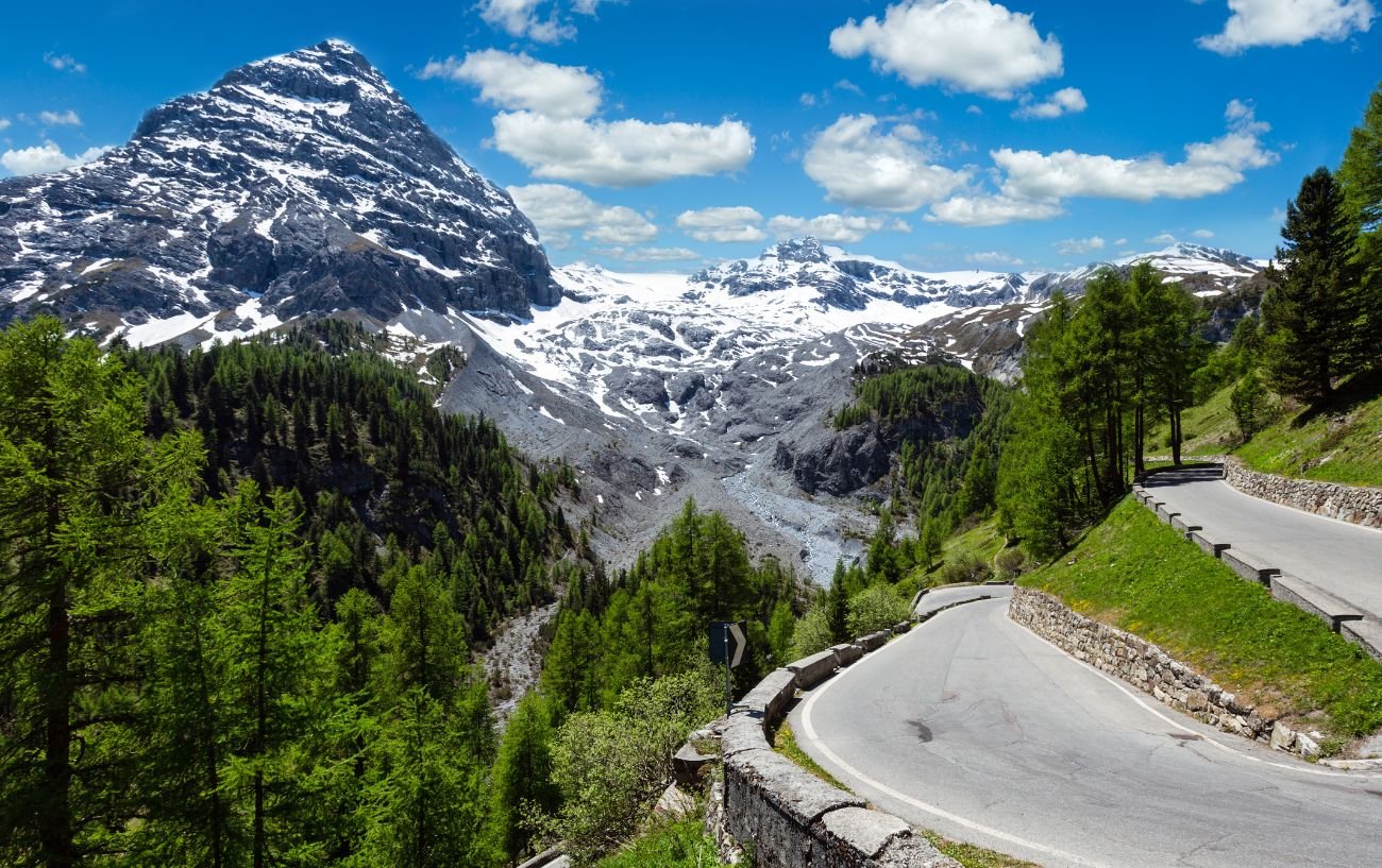 A hairpin on the Stelvio Pass with a view of snow-capped mountains.