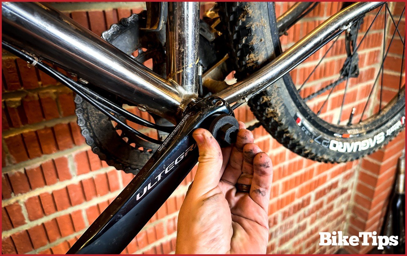 Using a crank removal tool on a black crank arm.